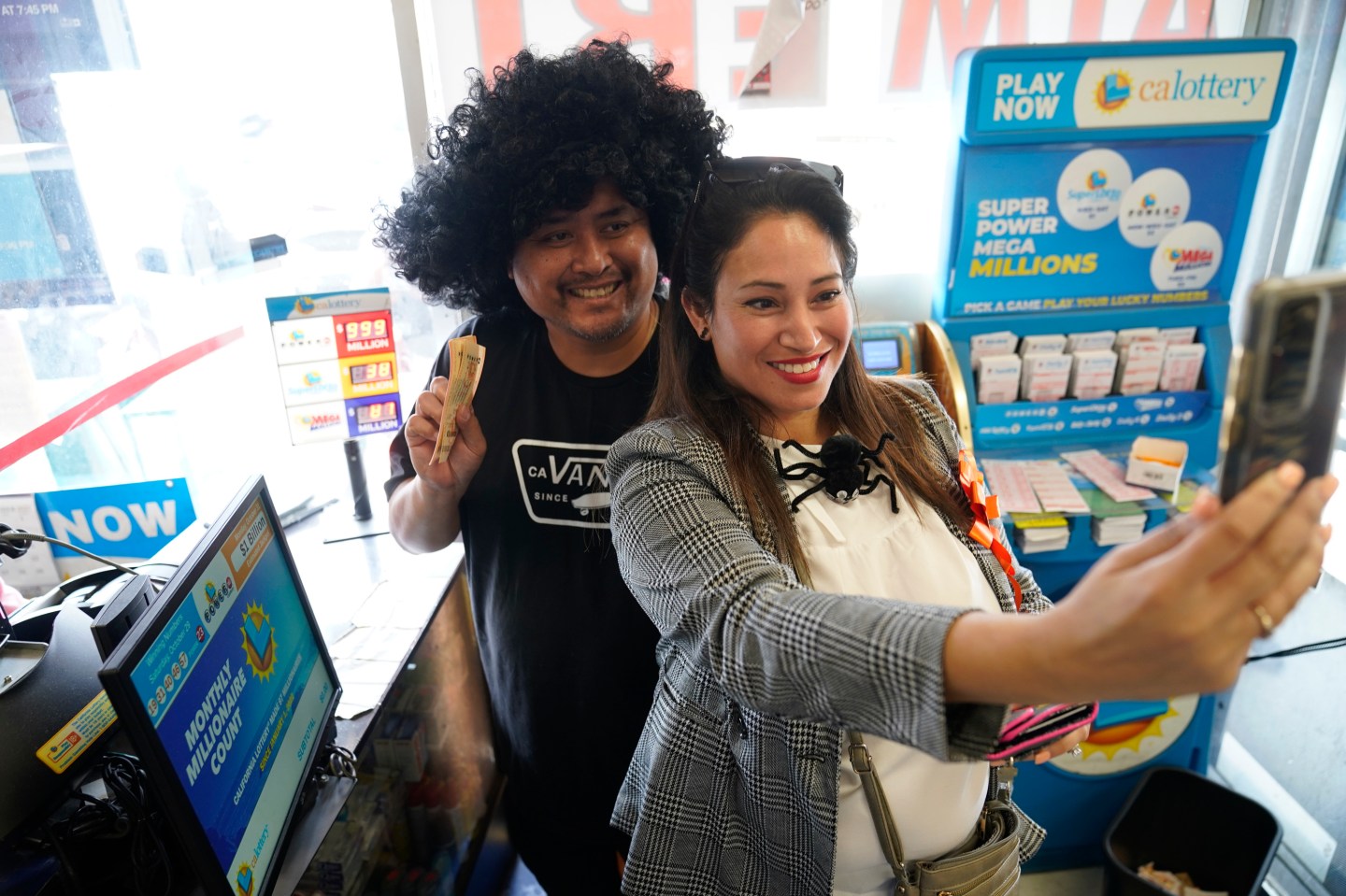 Cathy Zubiate, from Long Beach, Calif., and Gilbert Estrella, from Whitter, Calif., take a selfie after purchasing about $400.00 worth of lottery tickets for the Powerball lottery at the Blue Bird Liquor store in Hawthorne, Calif., on Oct. 31, 2022.