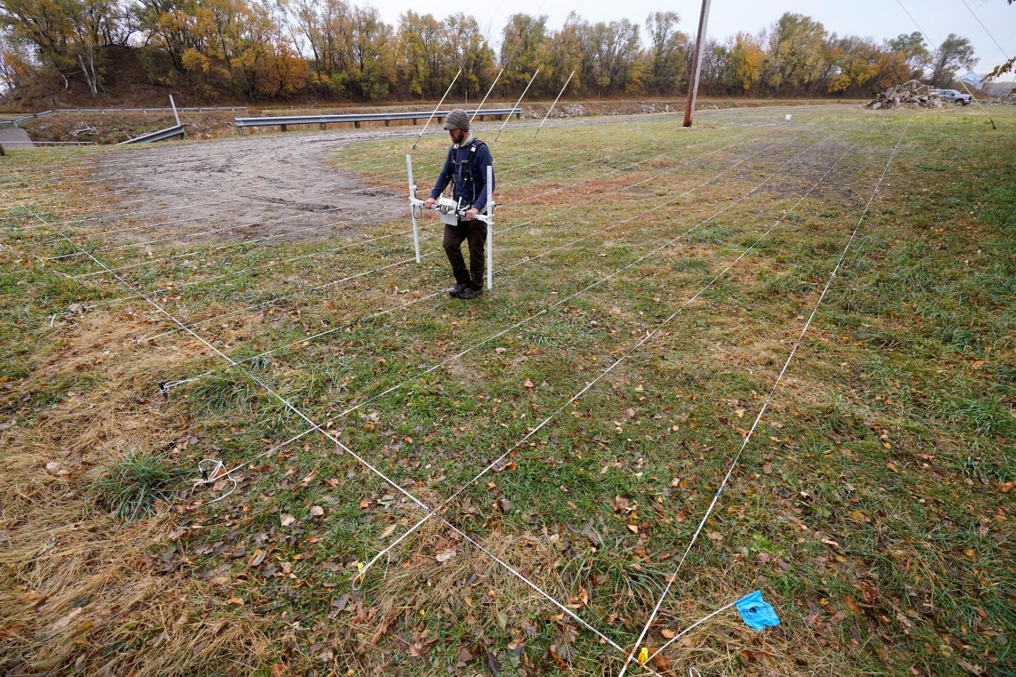 A man walks across a lawn using radar to find graves.