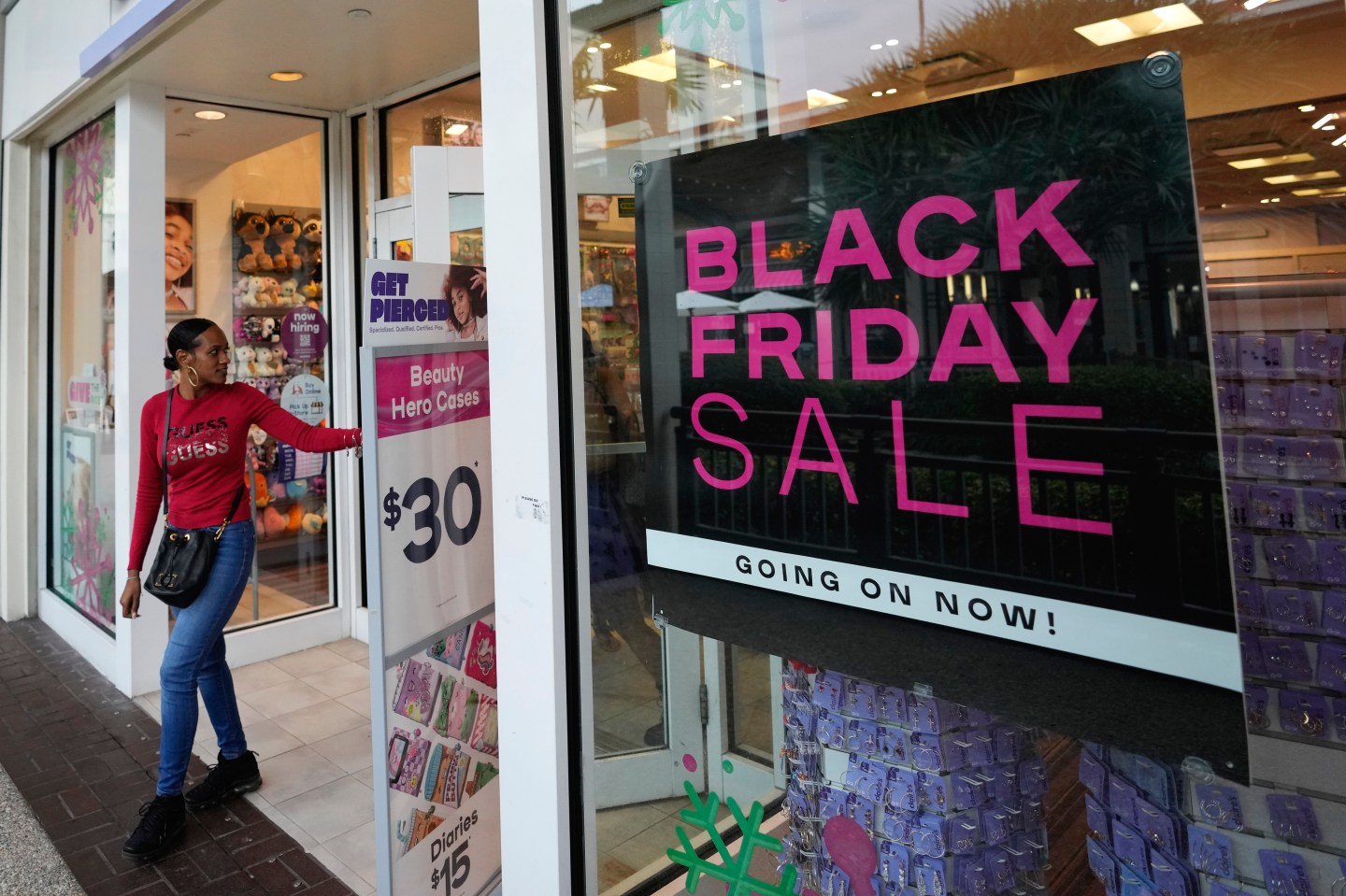 Shoppers exit a Claire's accessories store advertising sales ahead of Black Friday and the Thanksgiving holiday, Nov. 21, 2022, in Miami. Retailers are ushering in the start of the holiday shopping season on the day after Thanksgiving, preparing for the biggest crowds since 2019.
