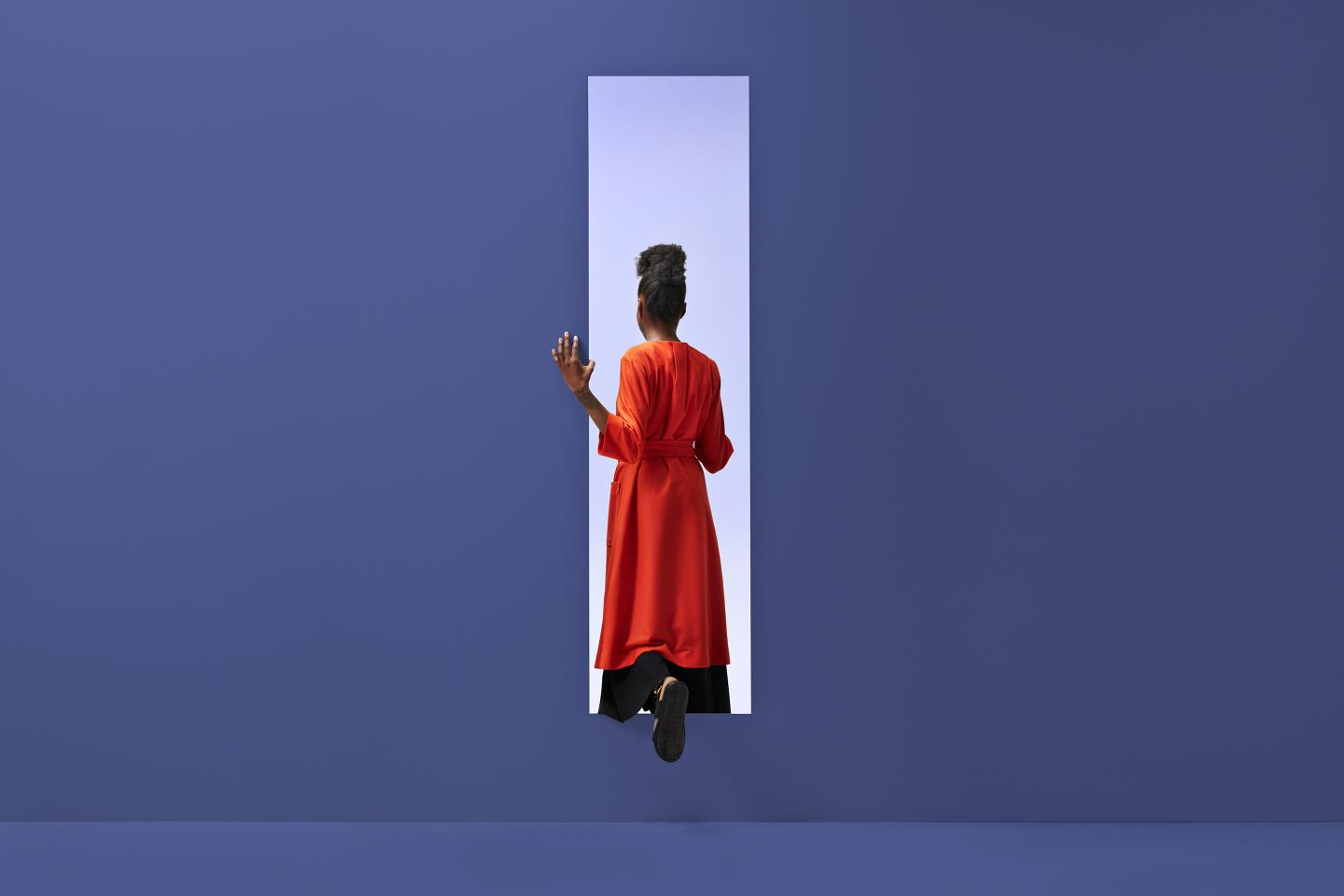 Black womam walking through a door in purple.