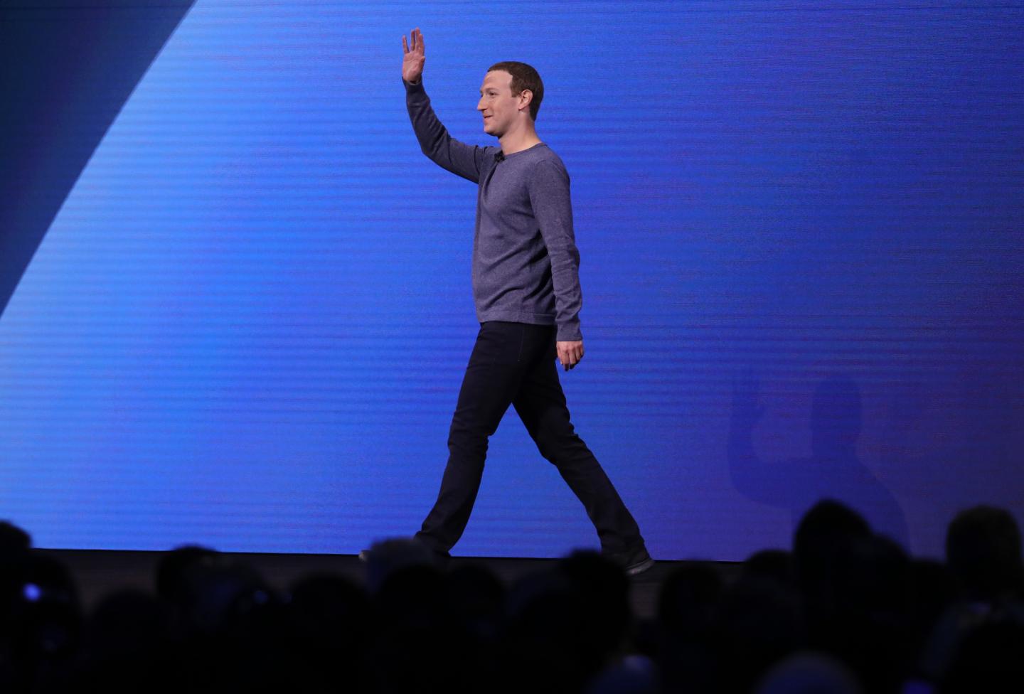 Mark Zuckerberg waves his hand as he walks