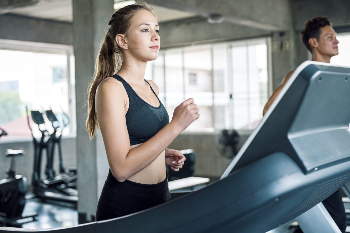 a young woman walking on a treadmill at a gym