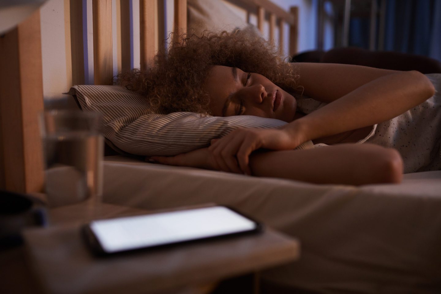 Sleeping young woman woken up by alarm