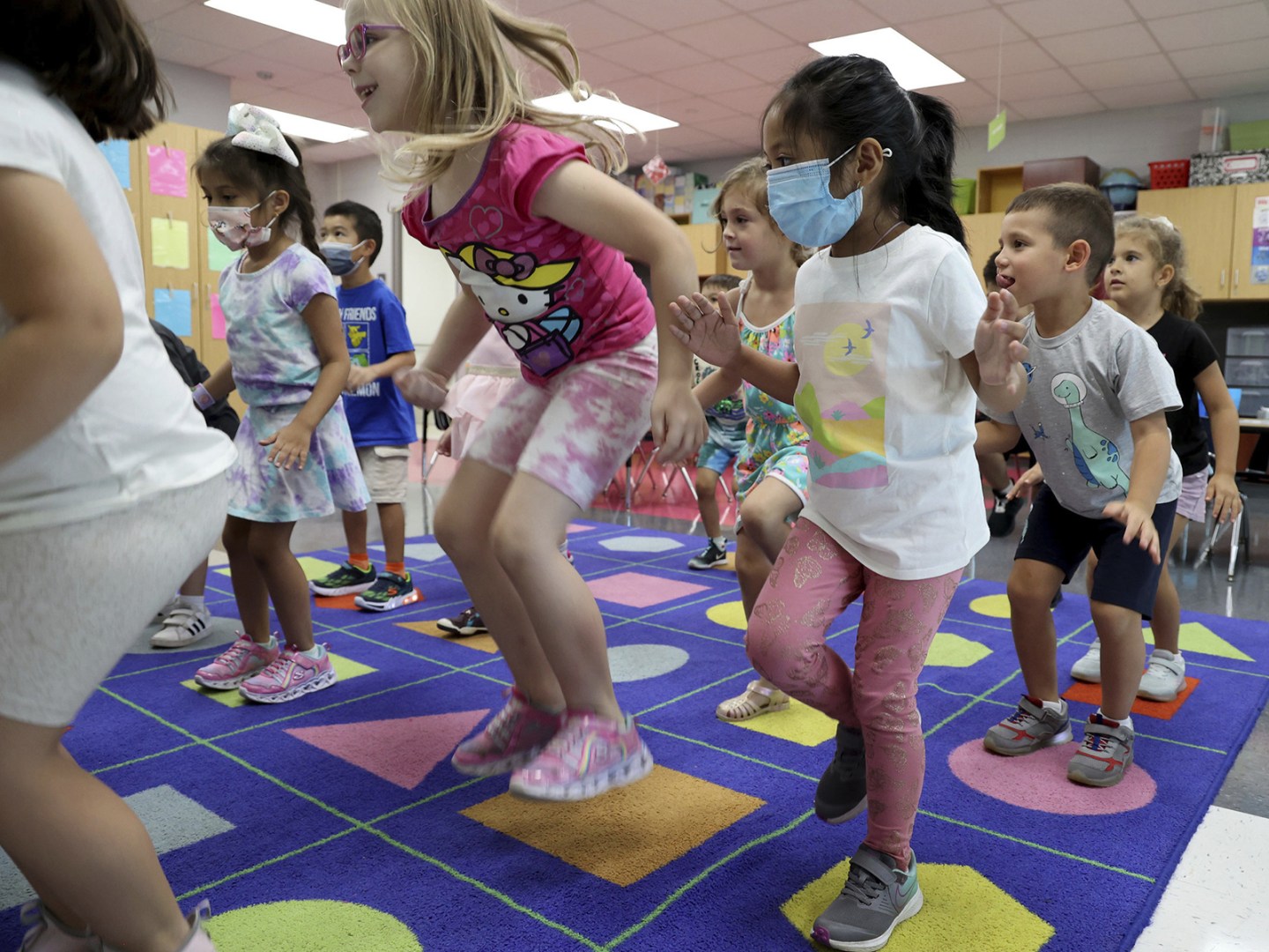 Kindergarteners, a few with face masks, sing and jump during class at Iroquois Community School in Des Plaines, Ill., on Aug. 5. 