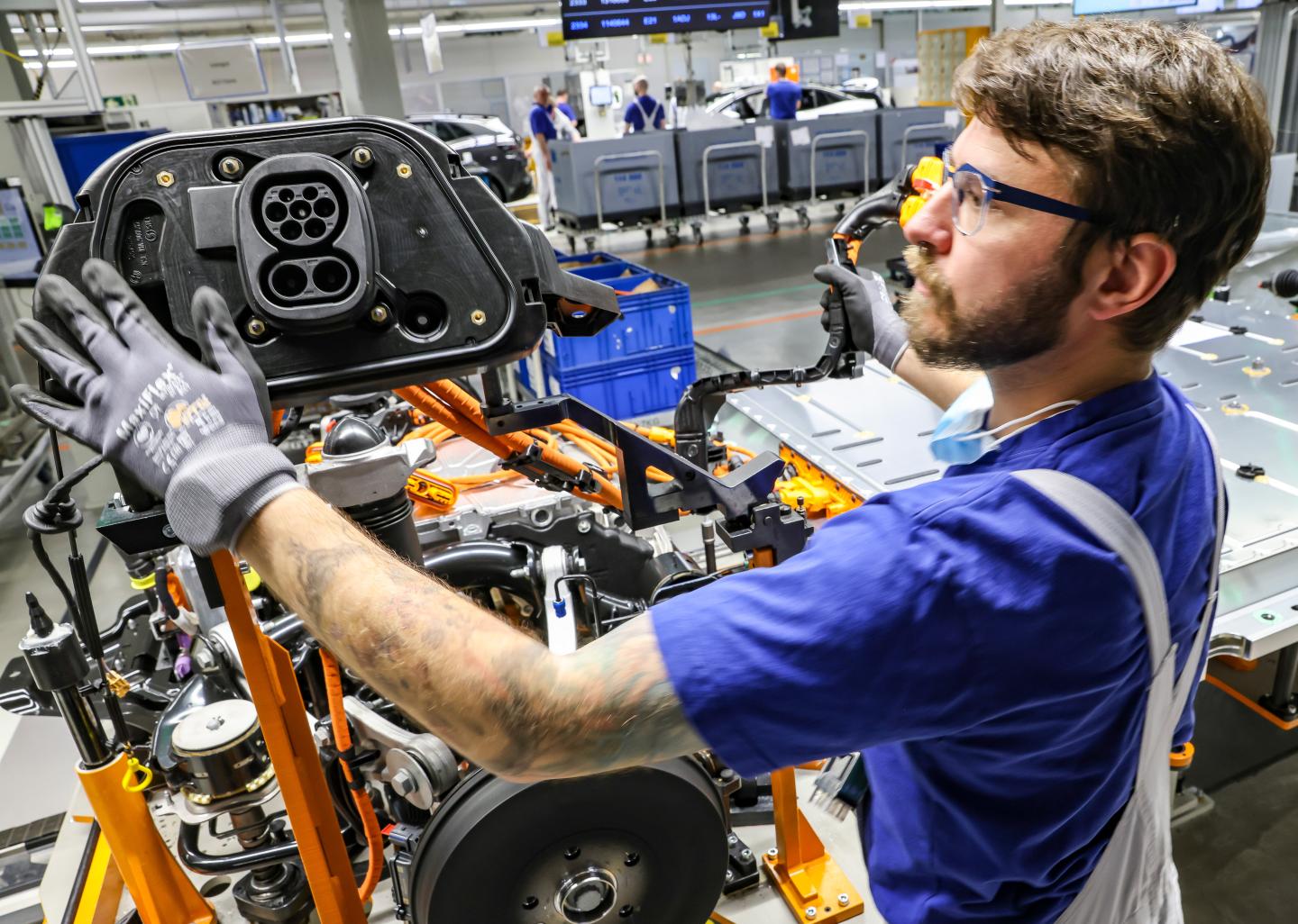 Shot of a Volkswagen employee assembling an electric vehicle in a plant.