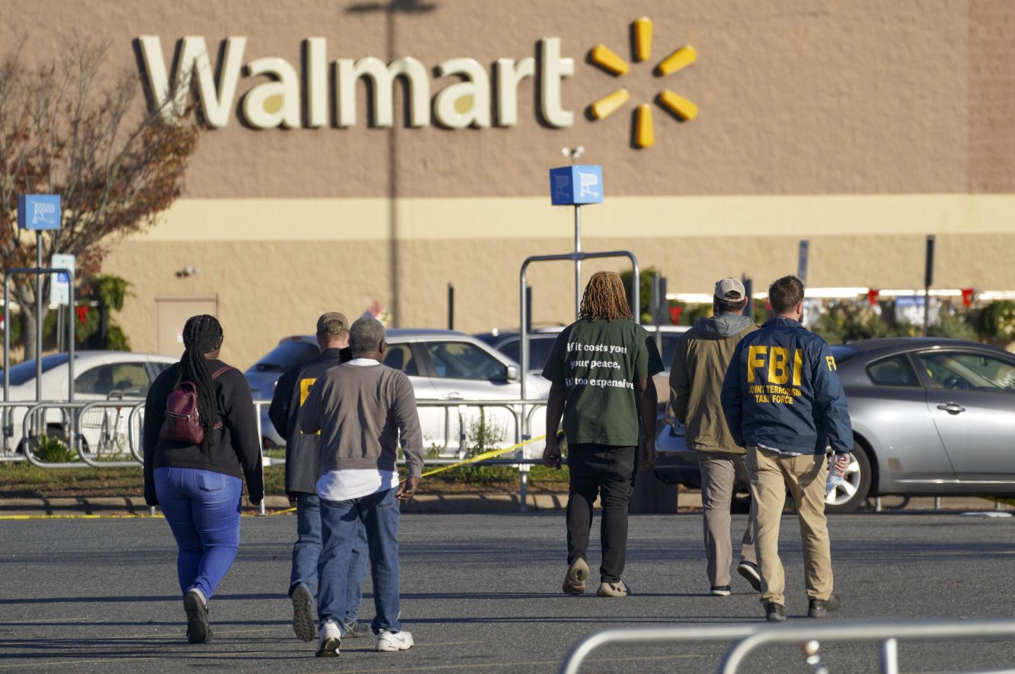 Investigators escort people to their cars outside a Walmart Supercenter where six people, including the shooter, were shot and killed