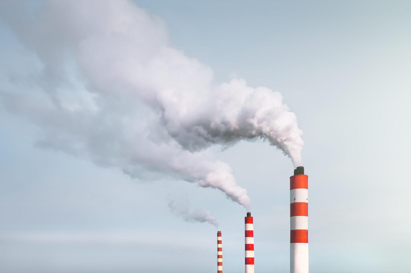 White smoke is pouring out of the chimneys of the power plant.