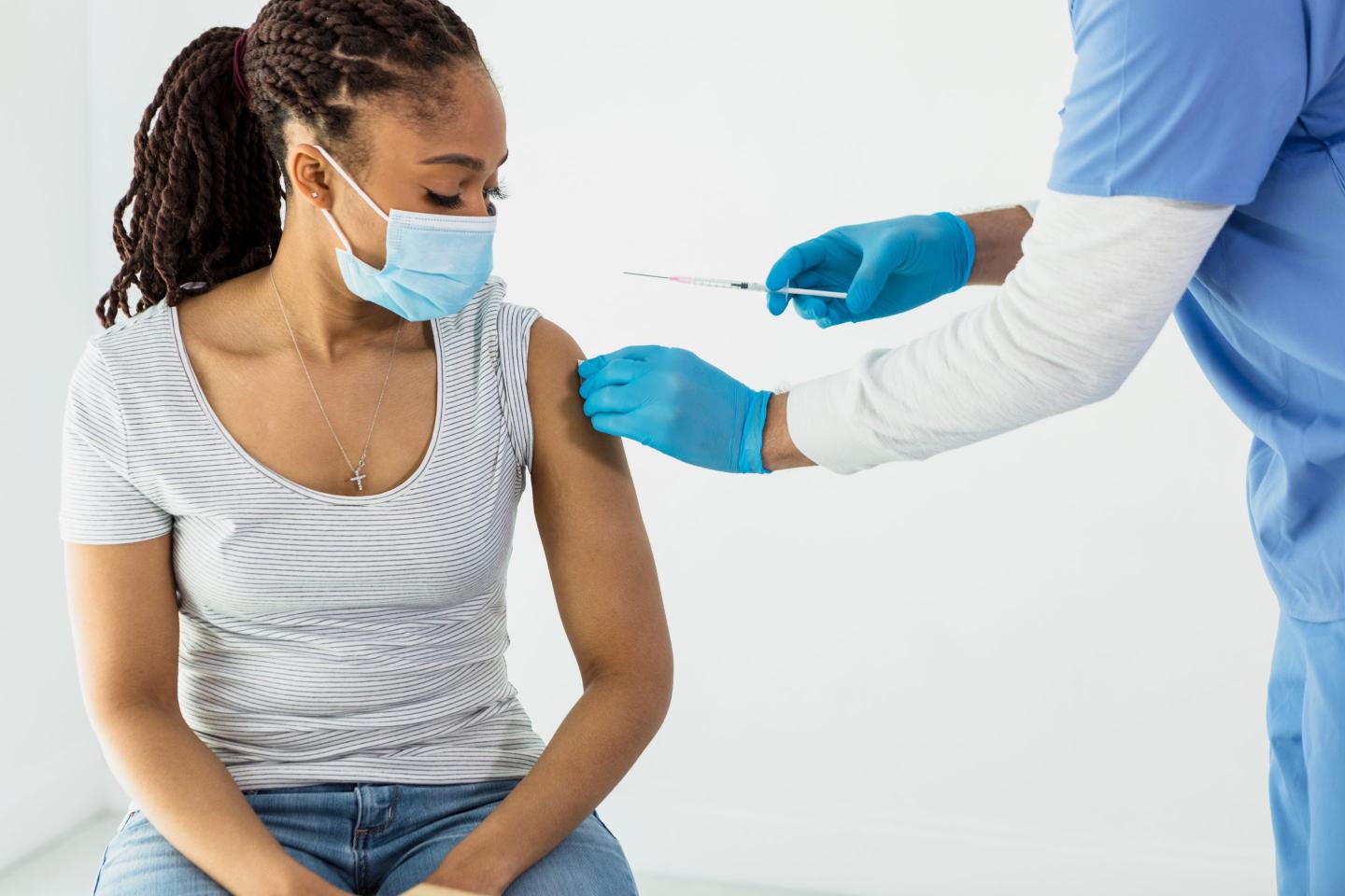 Female patient watches as a nurse preps arm for vaccination