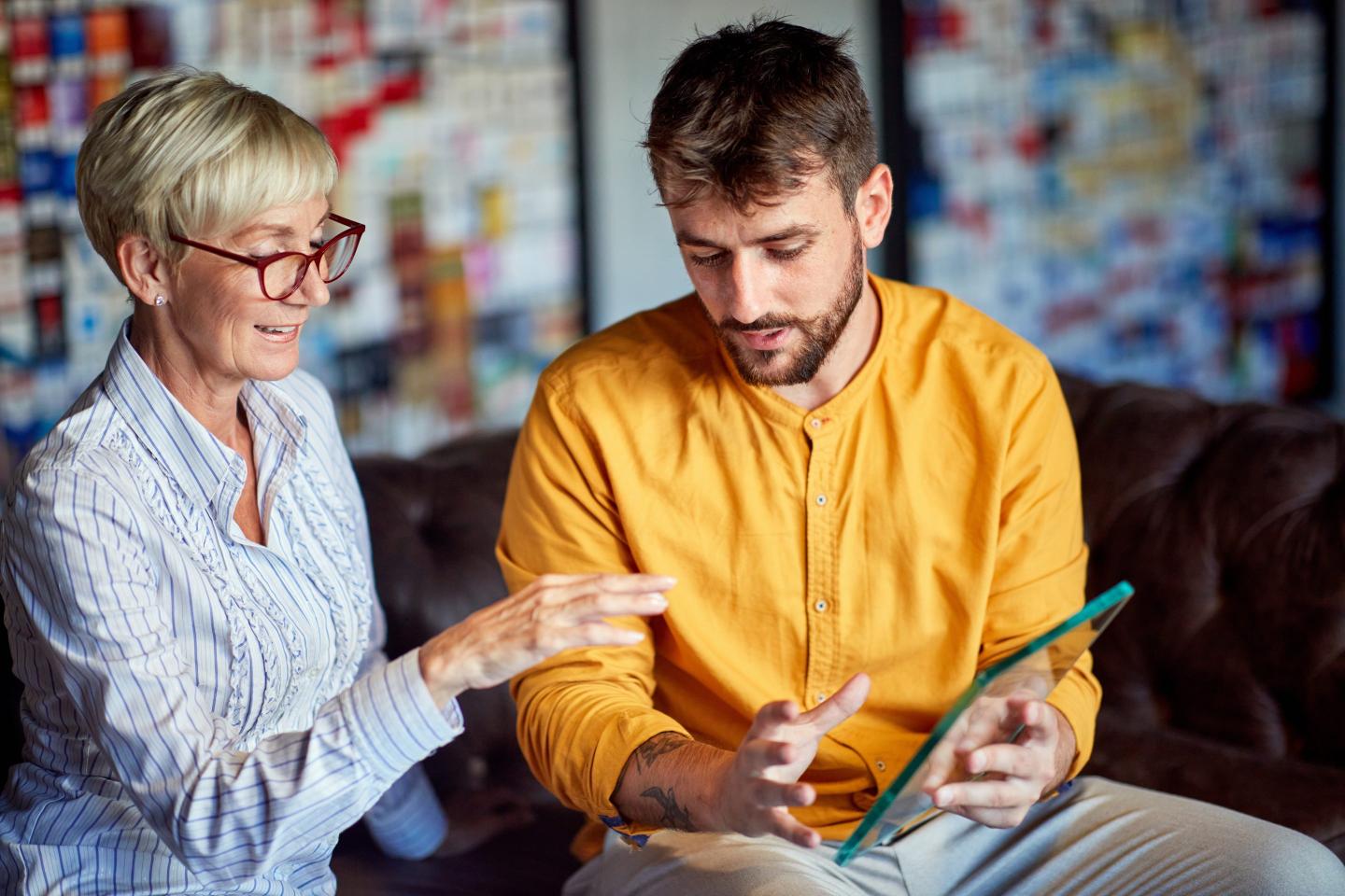 A older woman and younger man look at a tablet