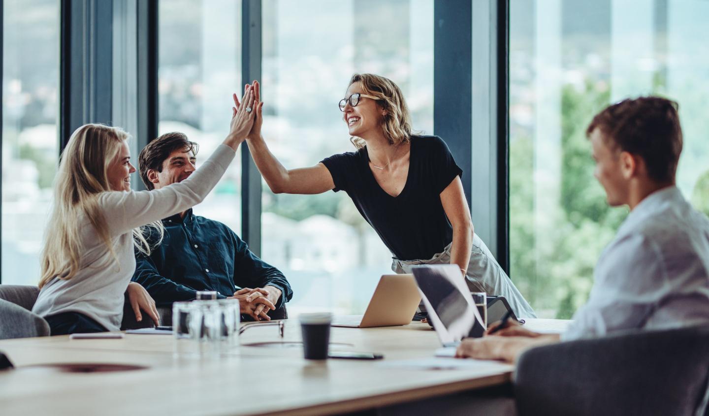 A employee high-fives another co-worker at a table