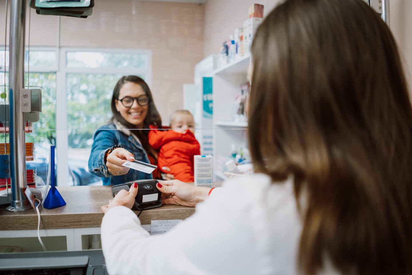 woman with a baby paying with a credit card at a pharmacy