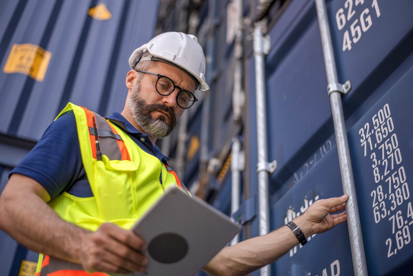 An engineer looking at a tablet next to a container unit used for shipping