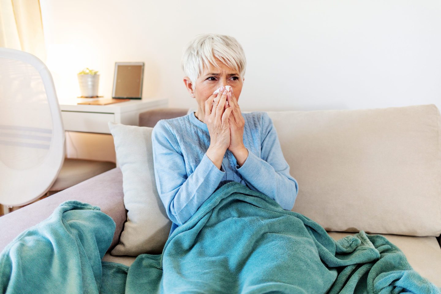 Mature woman blowing nose at home