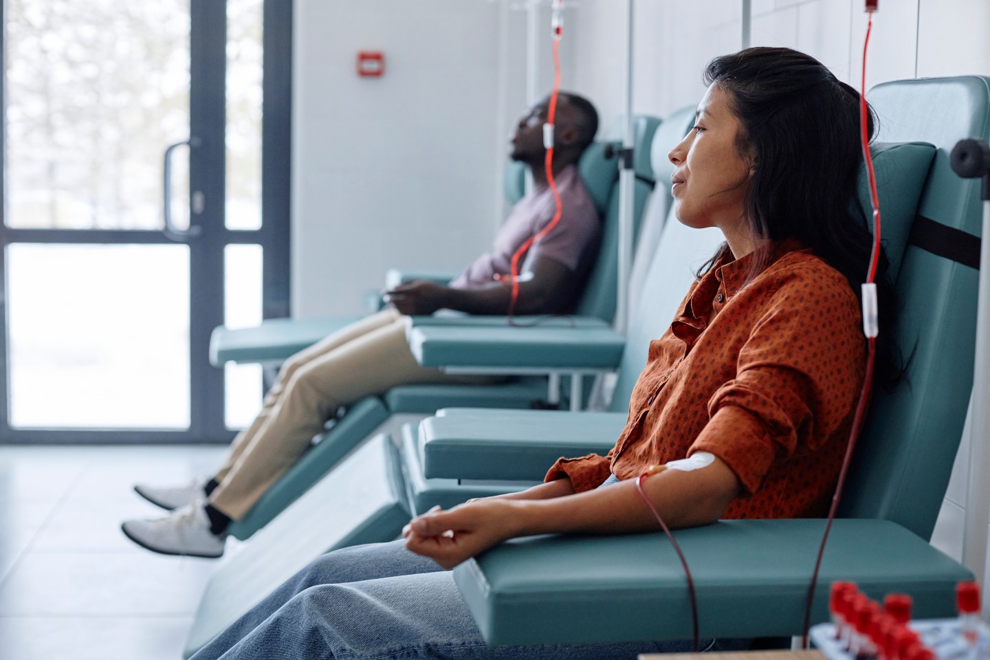 A man and a woman are seen donating blood in a hospital