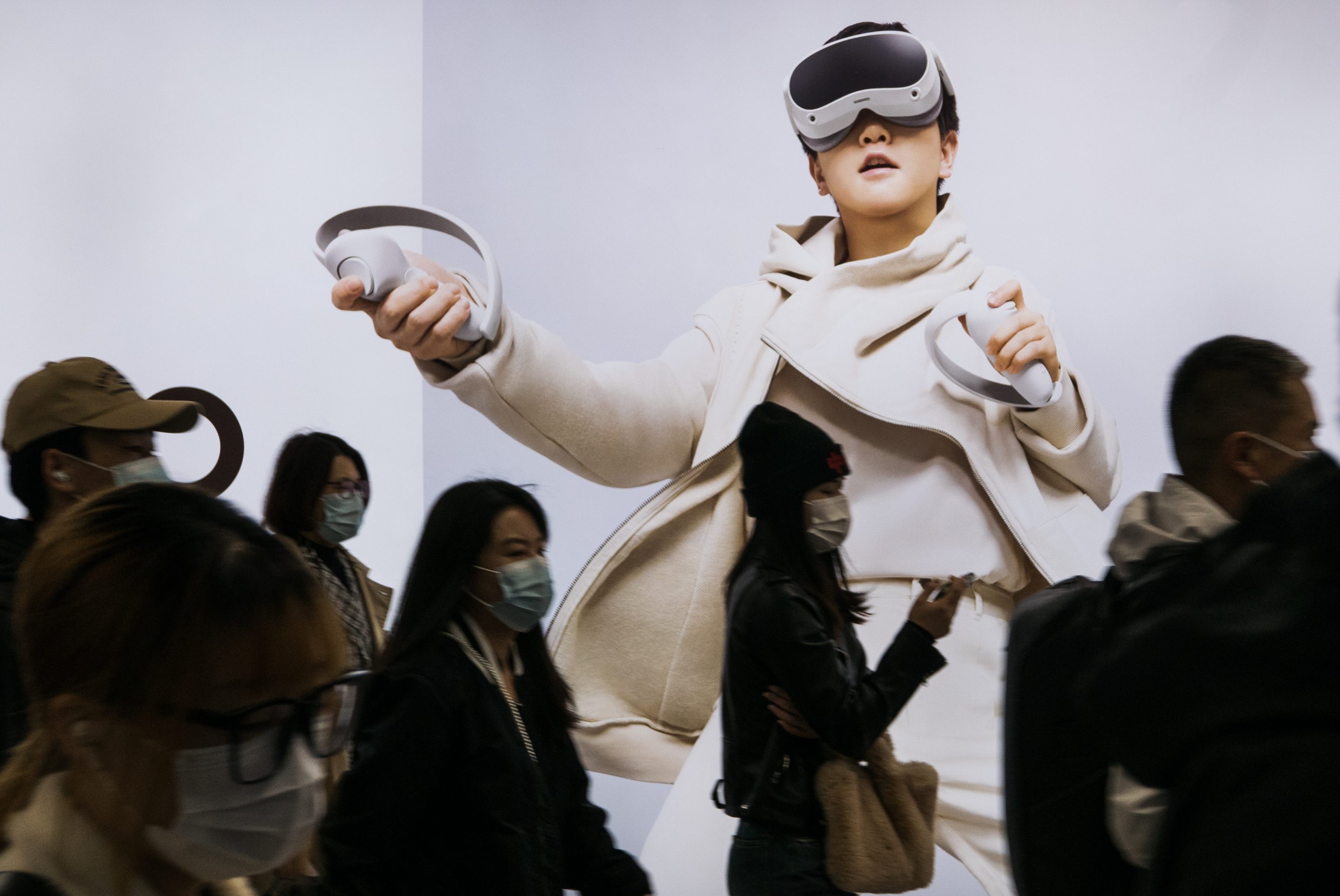 People walk past an ad for a VR headset in a Beijing subway station on 19 October.