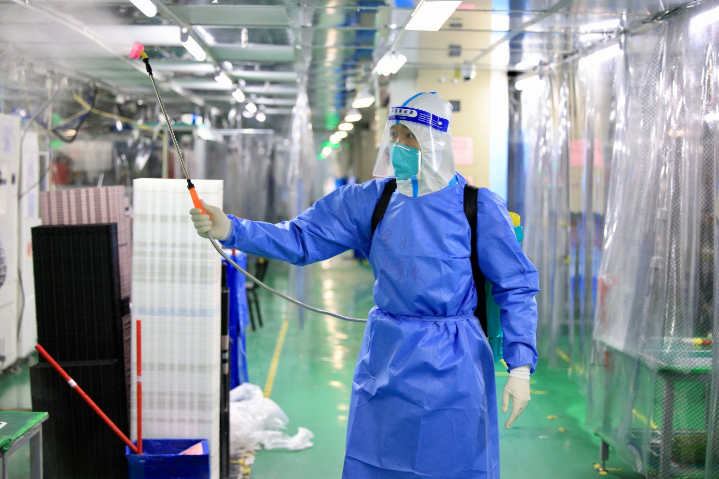 A Chinese healthcare worker wearing protective gear sprays down and disinfects a closed-down iPhone manufacturing facility in Henan province