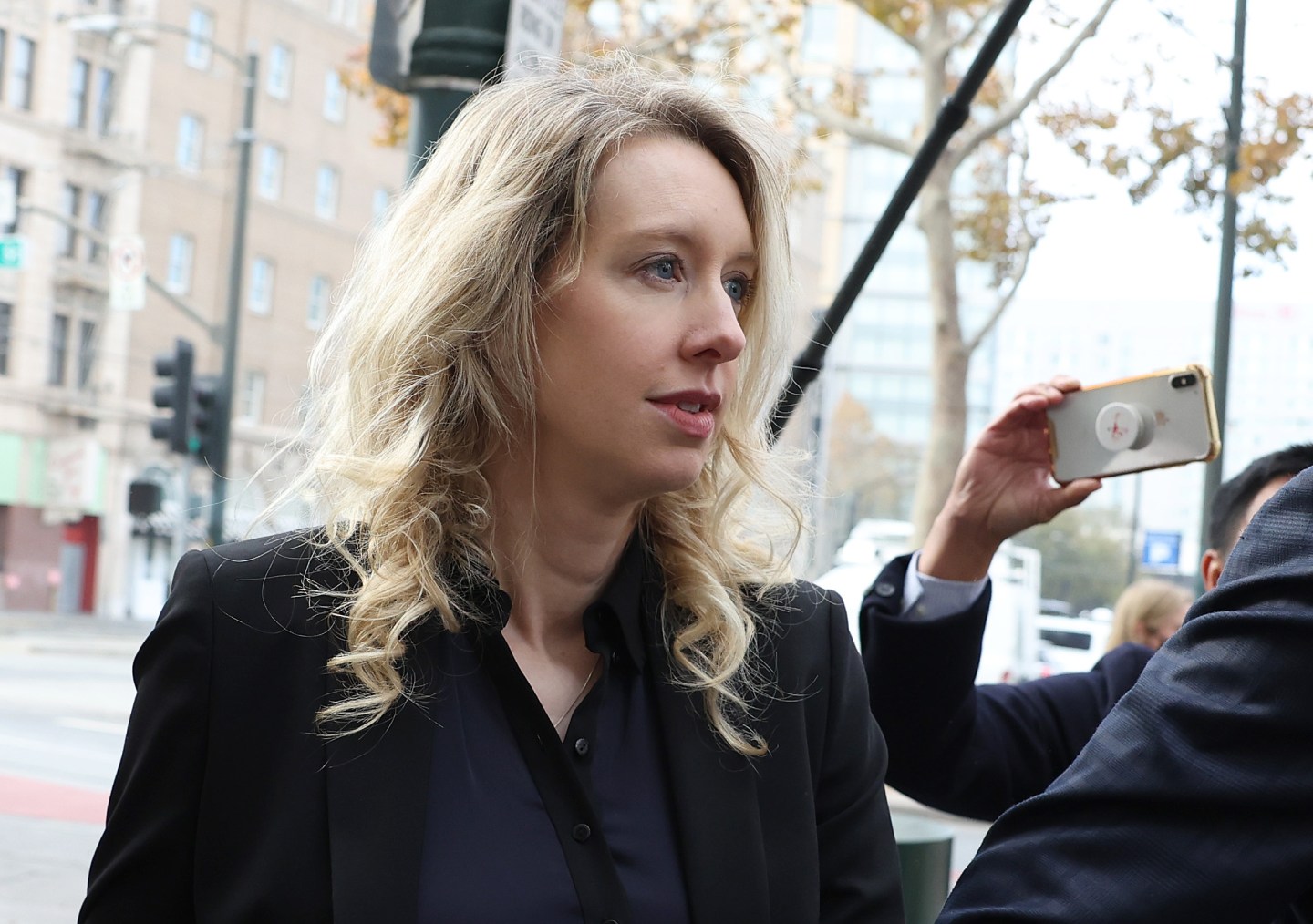 A middle-aged white woman with blonde hair, walks outside of a federal court building