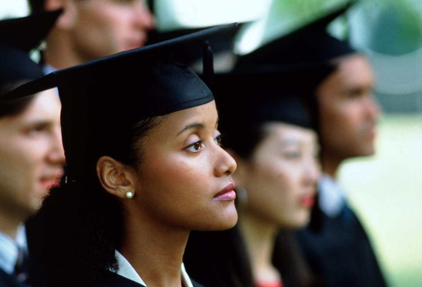 Shot of young woman wearing a cap and gown during her graduation ceremony
