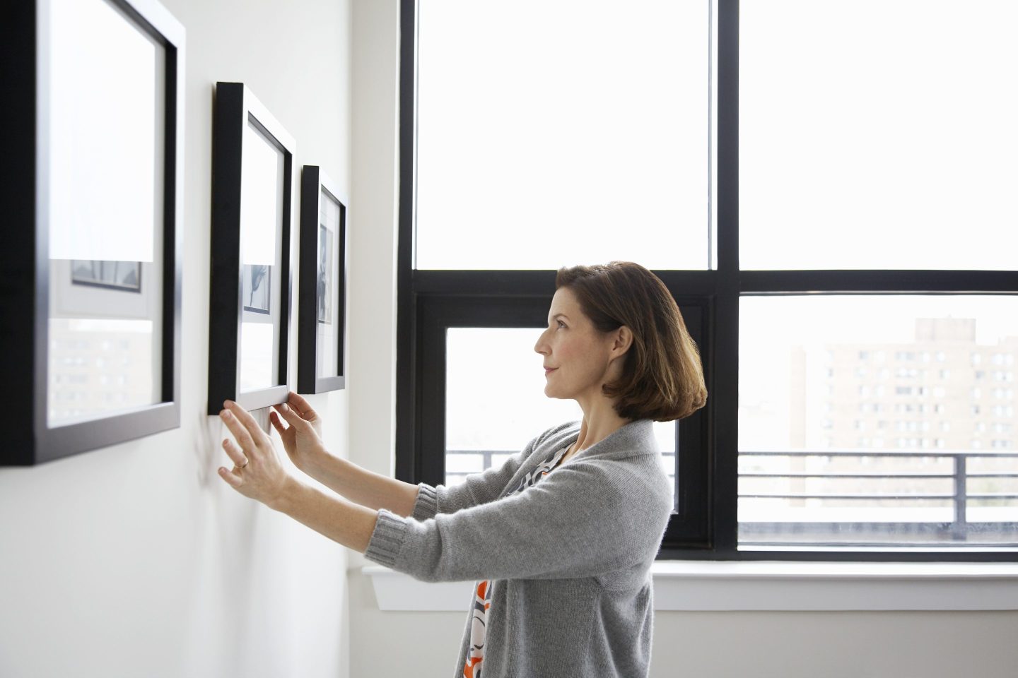 Woman adjusts a crooked picture frame