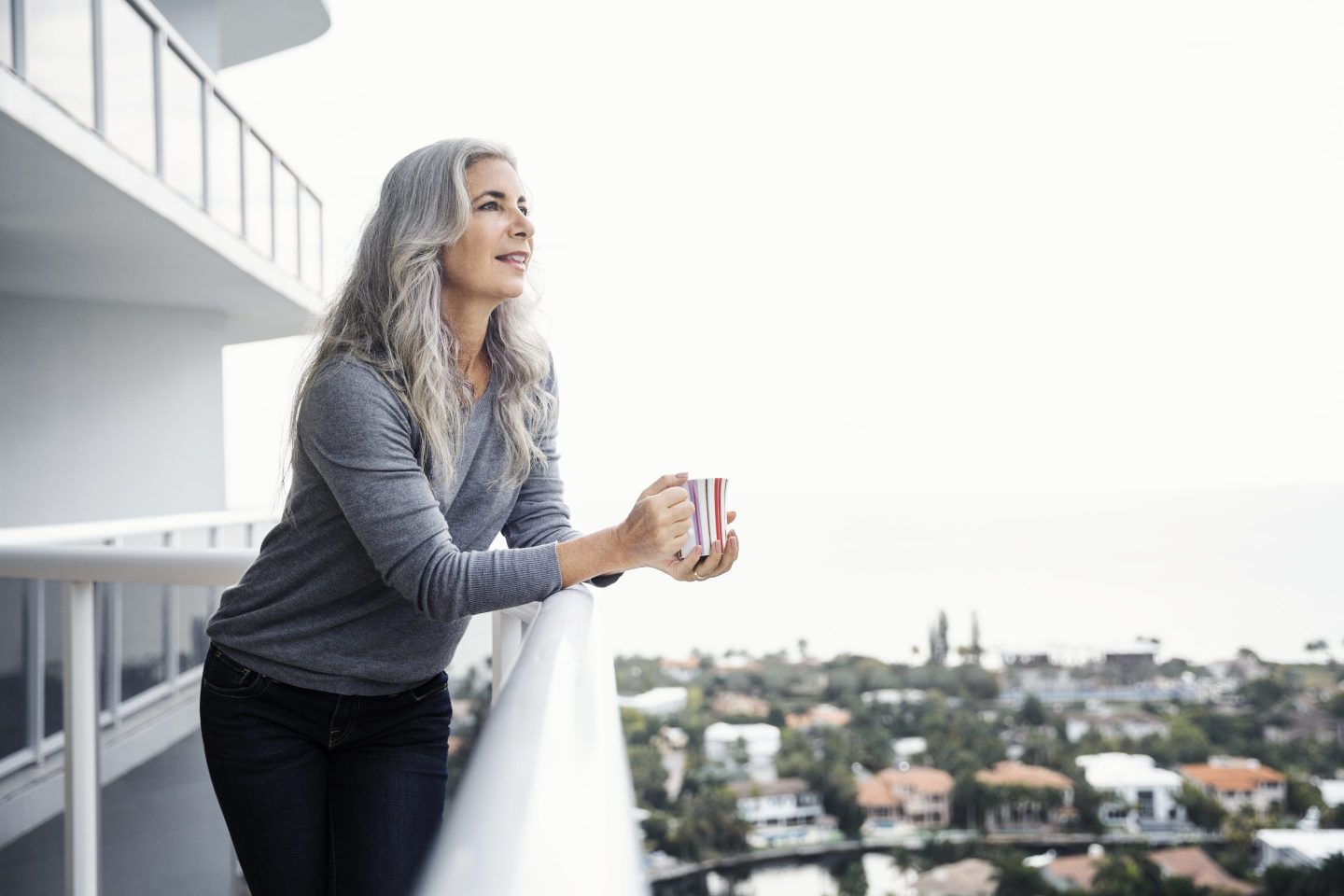 Woman holding coffee mug while standing on balcony in Florida
