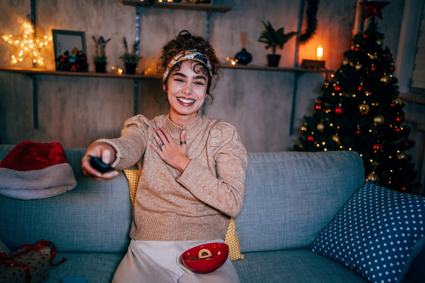 Young woman watching a comedy movie in the living room at night during cozy Christmas holidays.