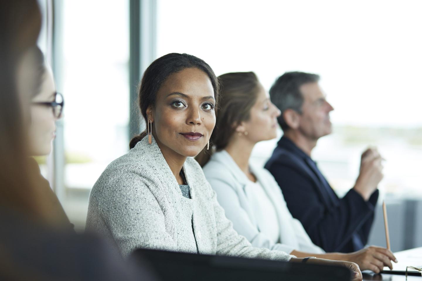 A Black woman executive in a conference room meeting smiles at the camera