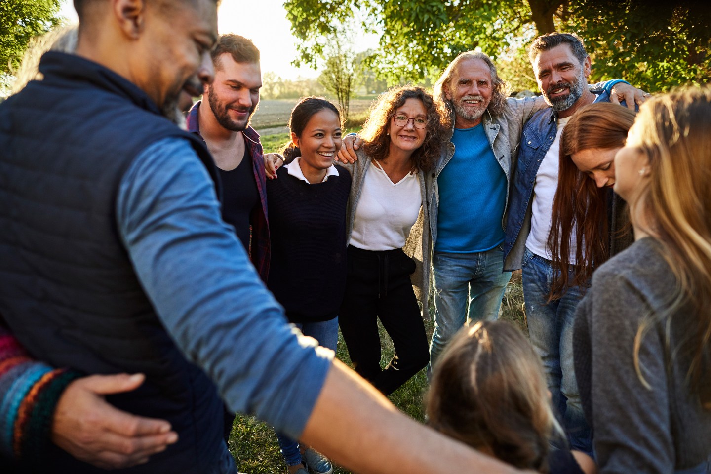 Group of happy people embracing on a garden party at sunset