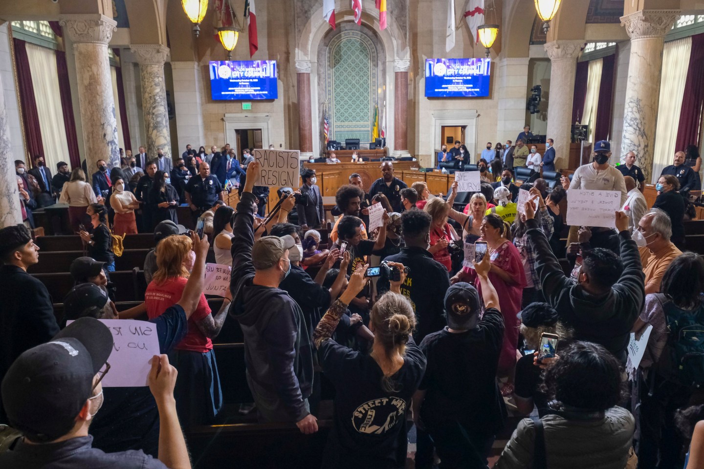 People hold signs and shout slogans before the cancellation of the Los Angeles City Council meeting