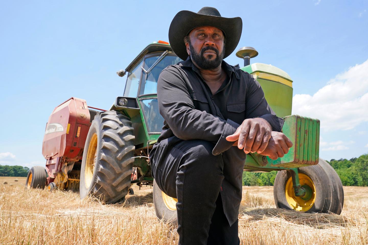 A farmer kneeling in front of a tractor