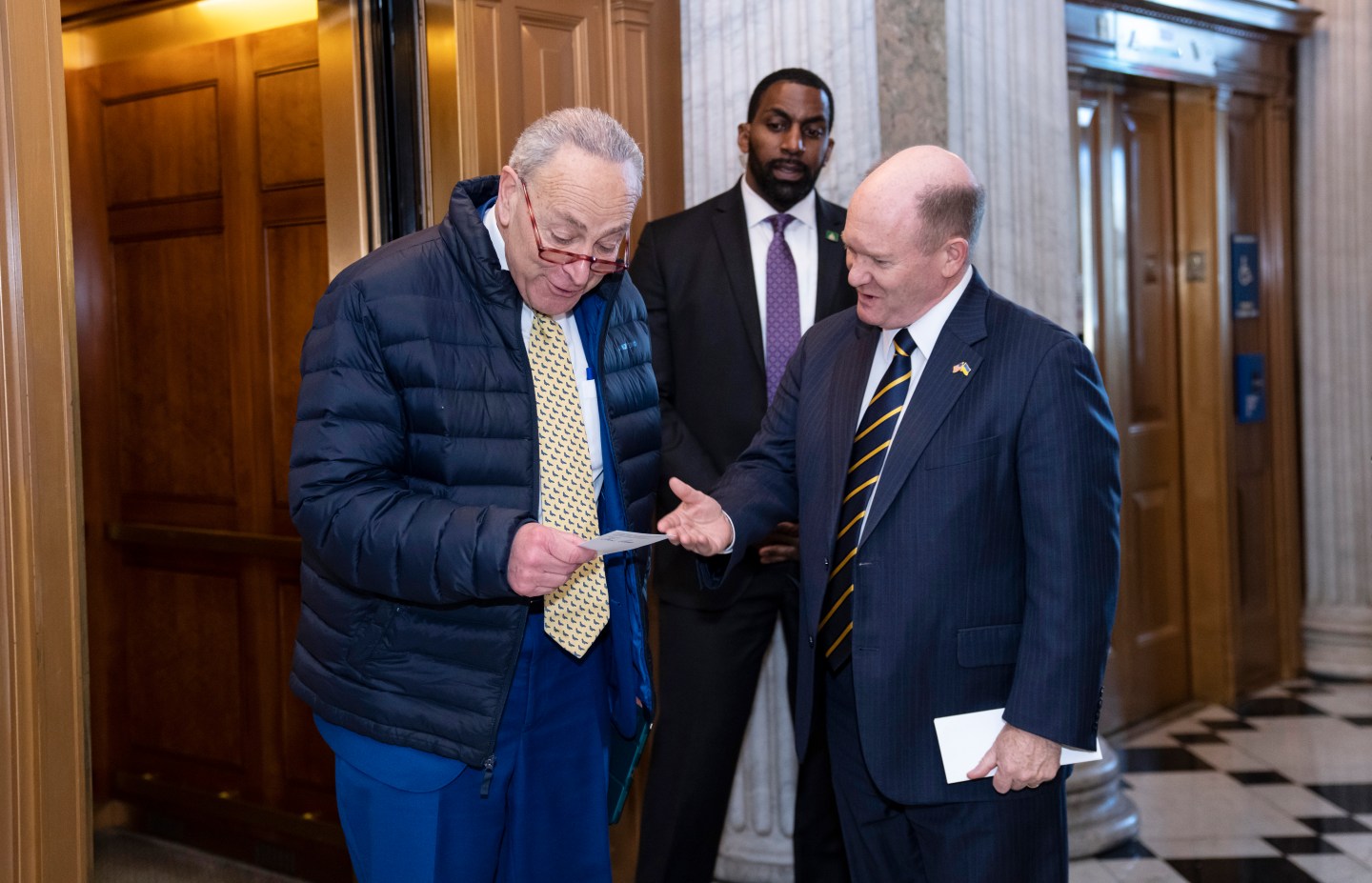 Senate Majority Leader Chuck Schumer, D-N.Y., left, confers with Sen. Chris Coons, D-Del., outside the chamber as lawmakers rush to complete passage of a $1.7 trillion bill to fund the government before a midnight Friday deadline or face the prospect of a partial government shutdown going into the Christmas holiday, at the Capitol in Washington, Dec. 21, 2022.