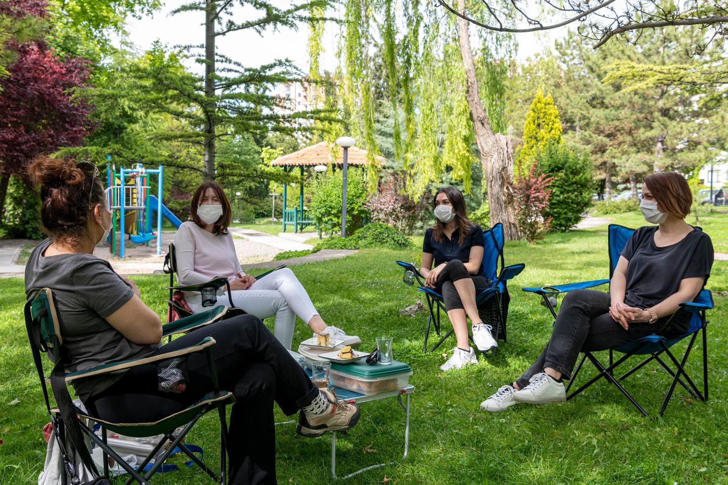 Four women with face masks sitting and chatting