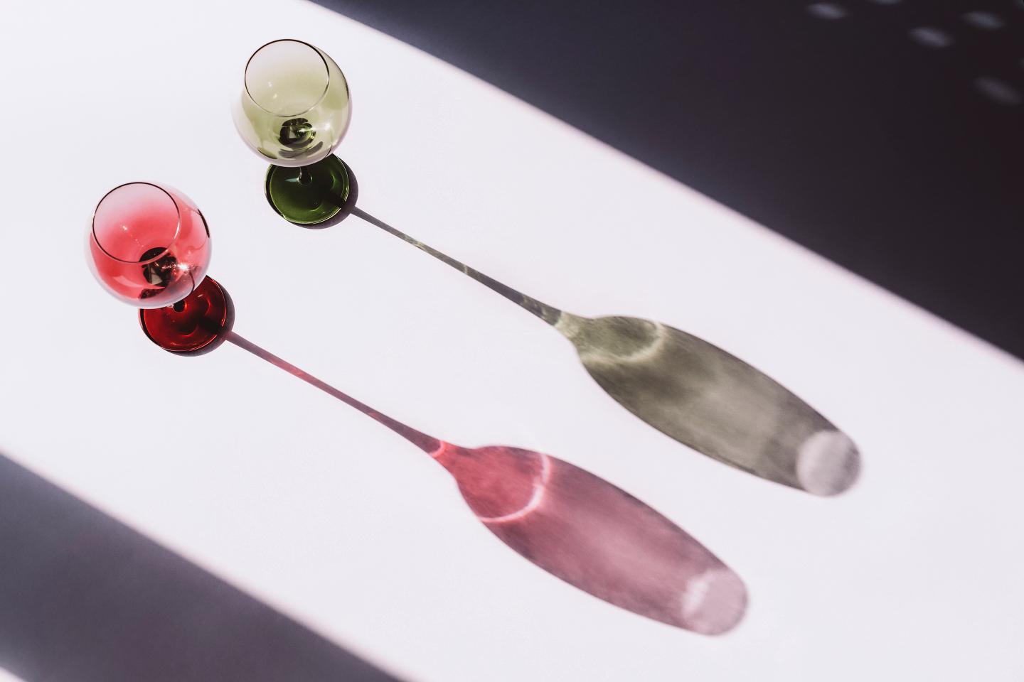 Two wine glasses on white background with light and shadow, top view.