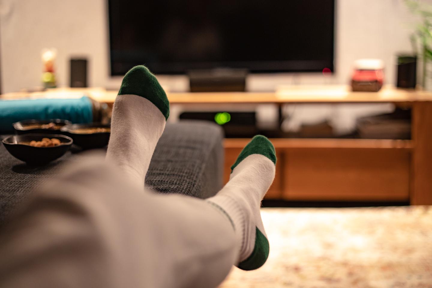 An unseen person watches TV with their feet up