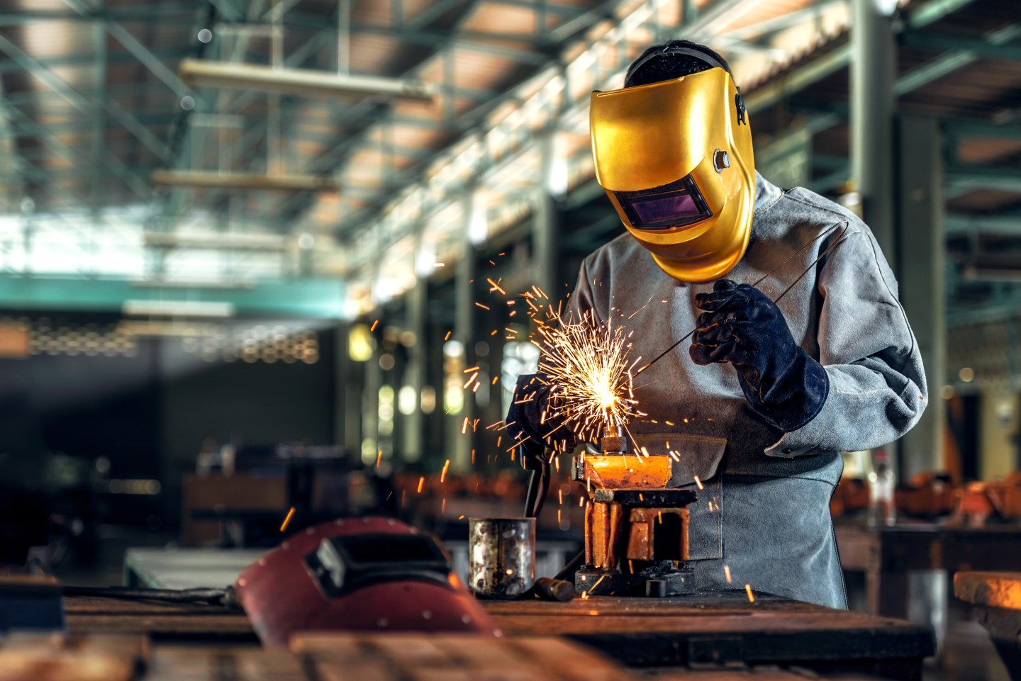 A factory worker with a welding mask on.