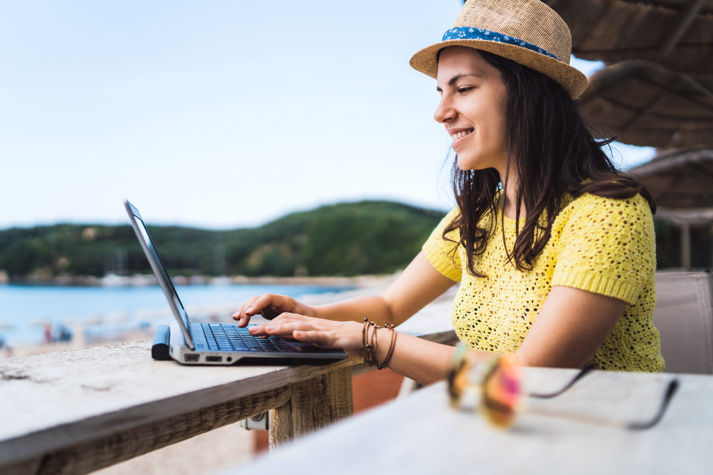 A young woman working while at a beach cafe.