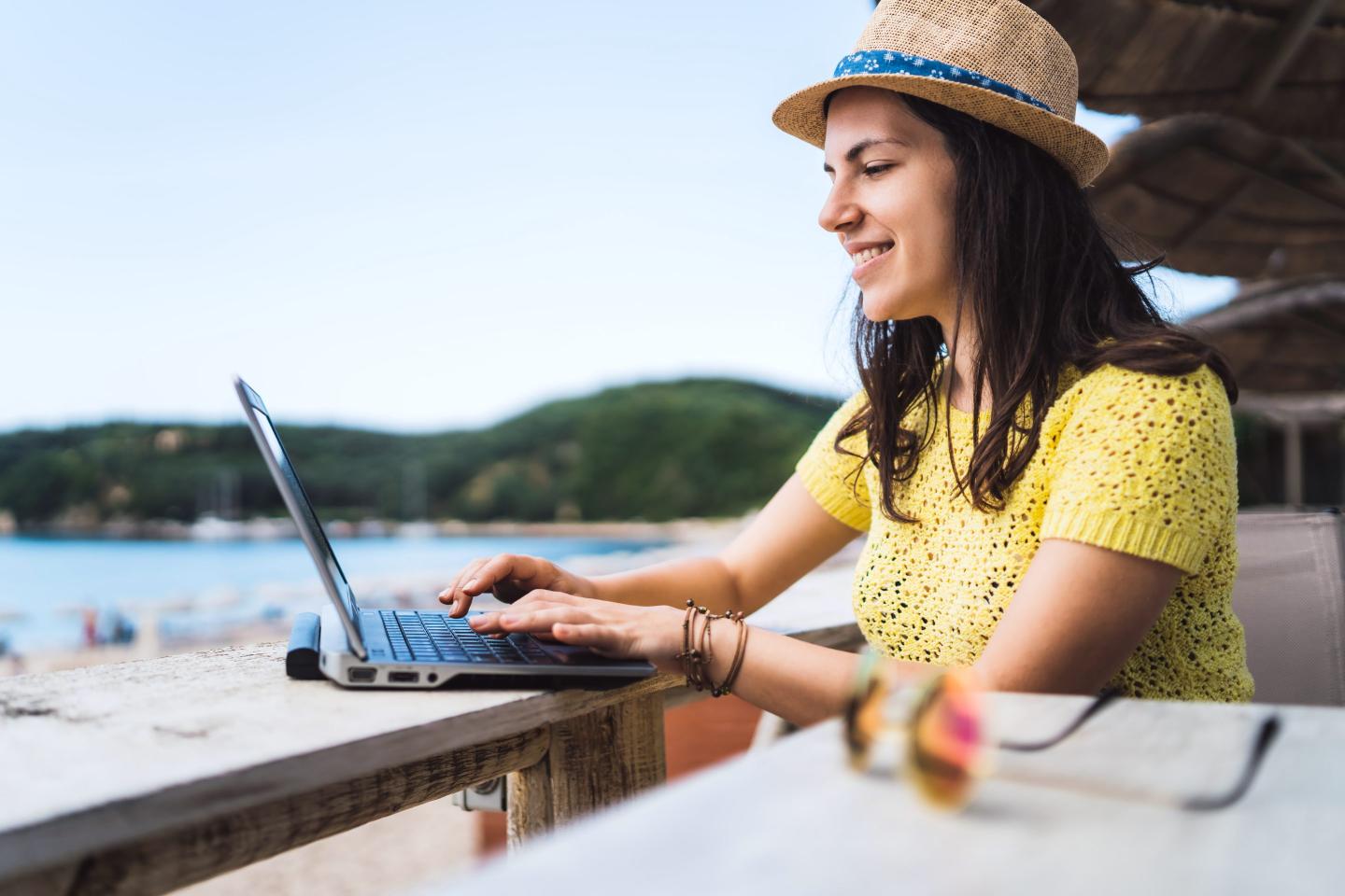 A young woman working while at a beach cafe.