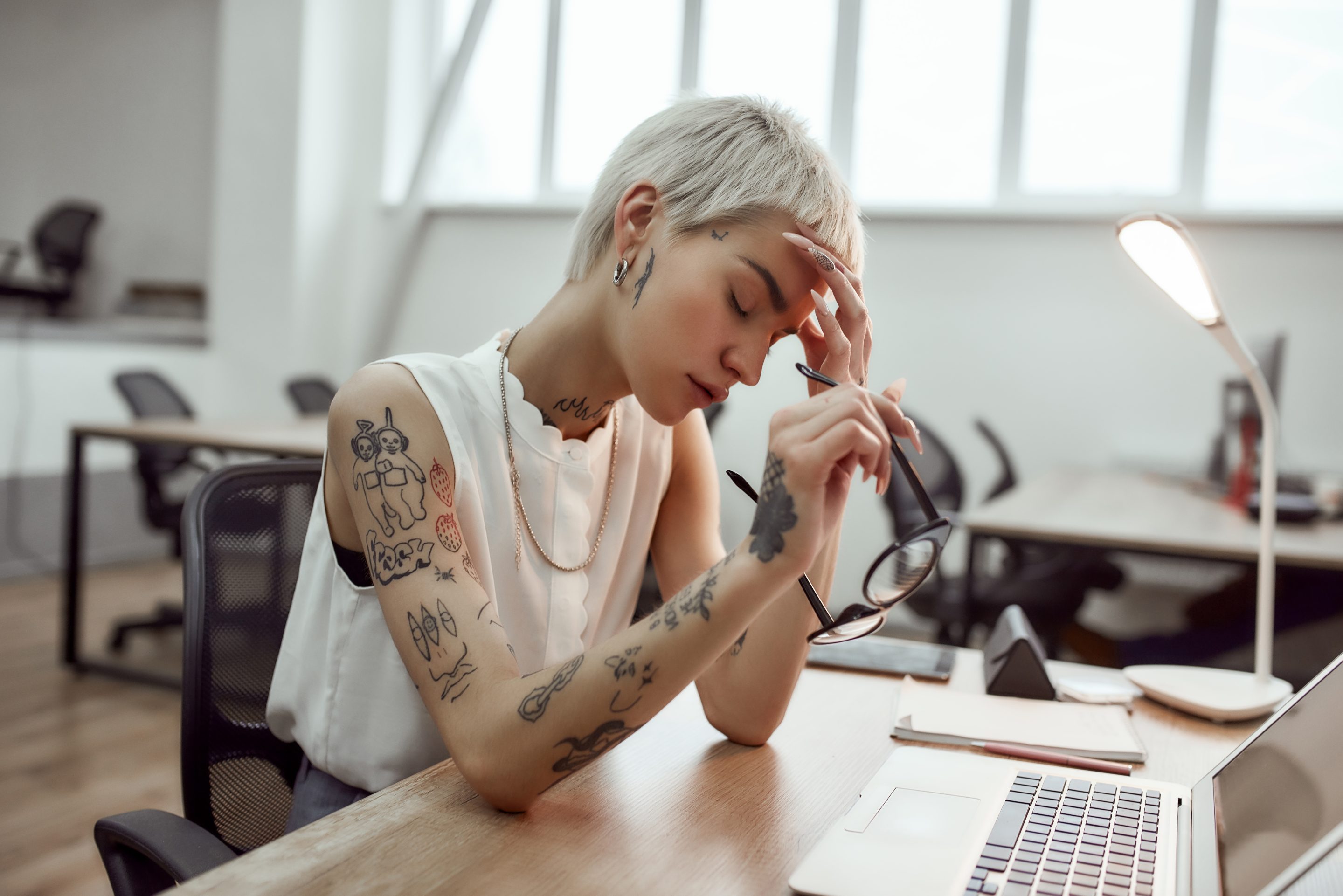 Woman with head in hand at work.