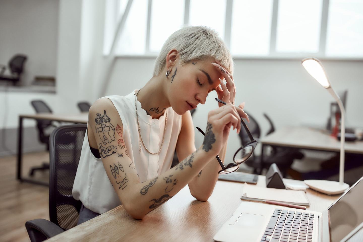 Woman with head in hand at work.