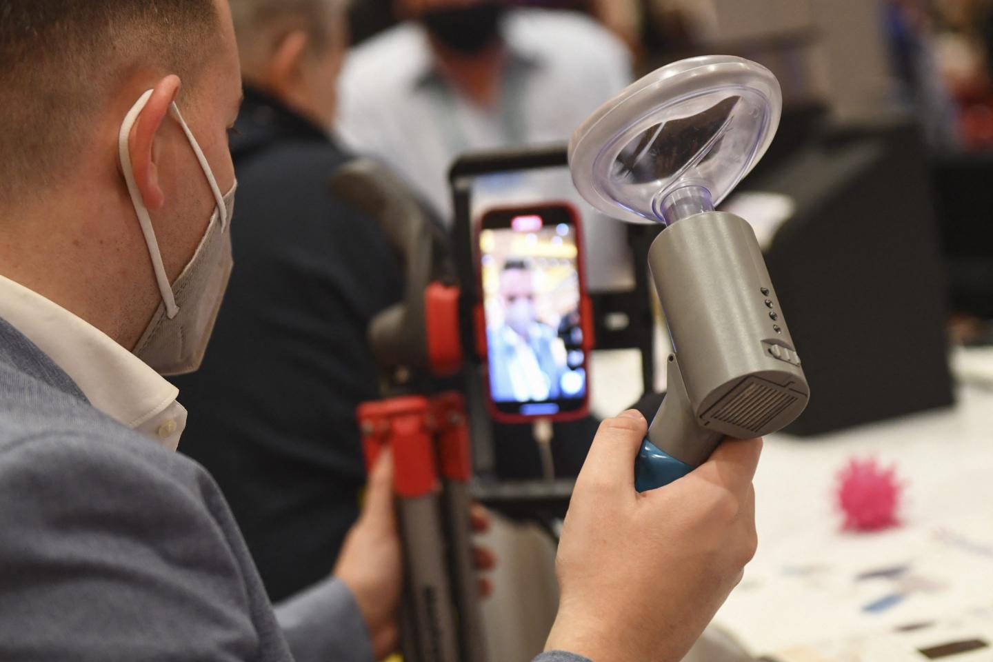 A trade show attendee with a handheld Covid-19 detection breath analyzer in Las Vegas