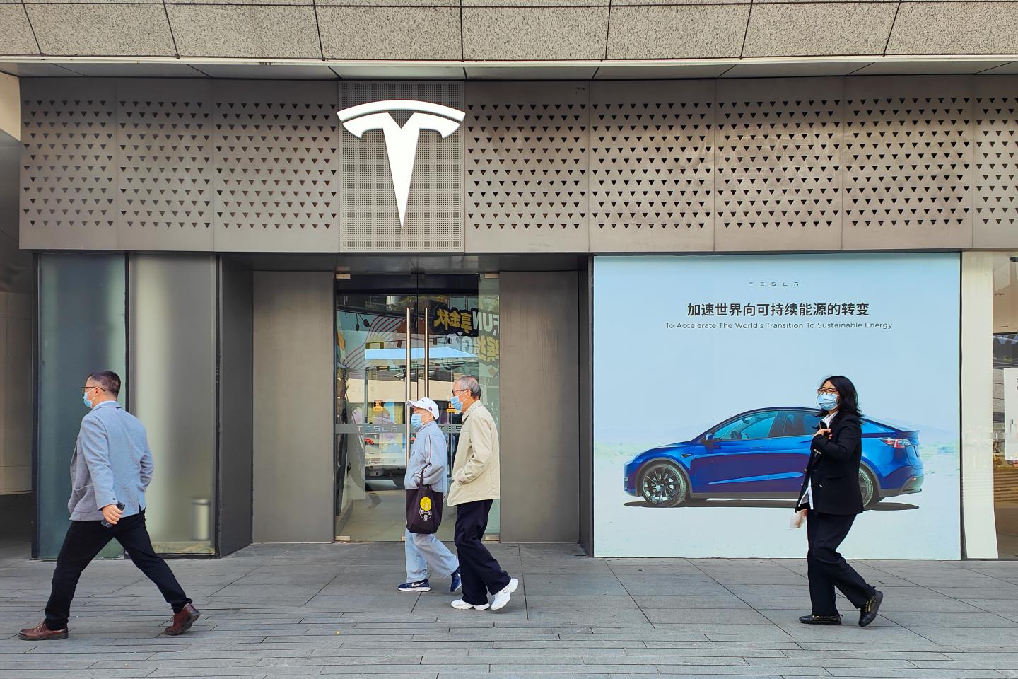 Pedestrians walk past a Tesla store in Shanghai, Nov. 15, 2022.