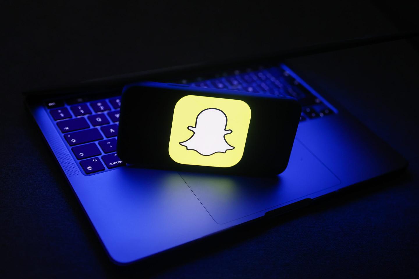 Snapchat logo displayed on a phone screen and a laptop