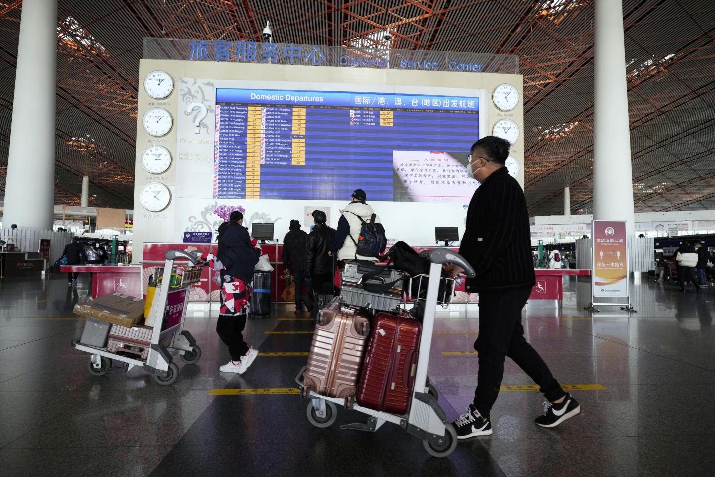 People walk with their suitcases through a departure lobby of Beijing Capital International Airport on Dec. 27, 2022. China said the previous day it will reopen borders and abandon quarantine measures that have been in place to stem the spread of coronavirus infections on Jan. 8, in a shift away from its strict "zero-COVID" policy.