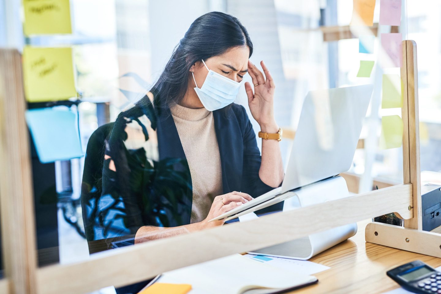 A young businesswoman suffering with a headache while working on a laptop in an office
