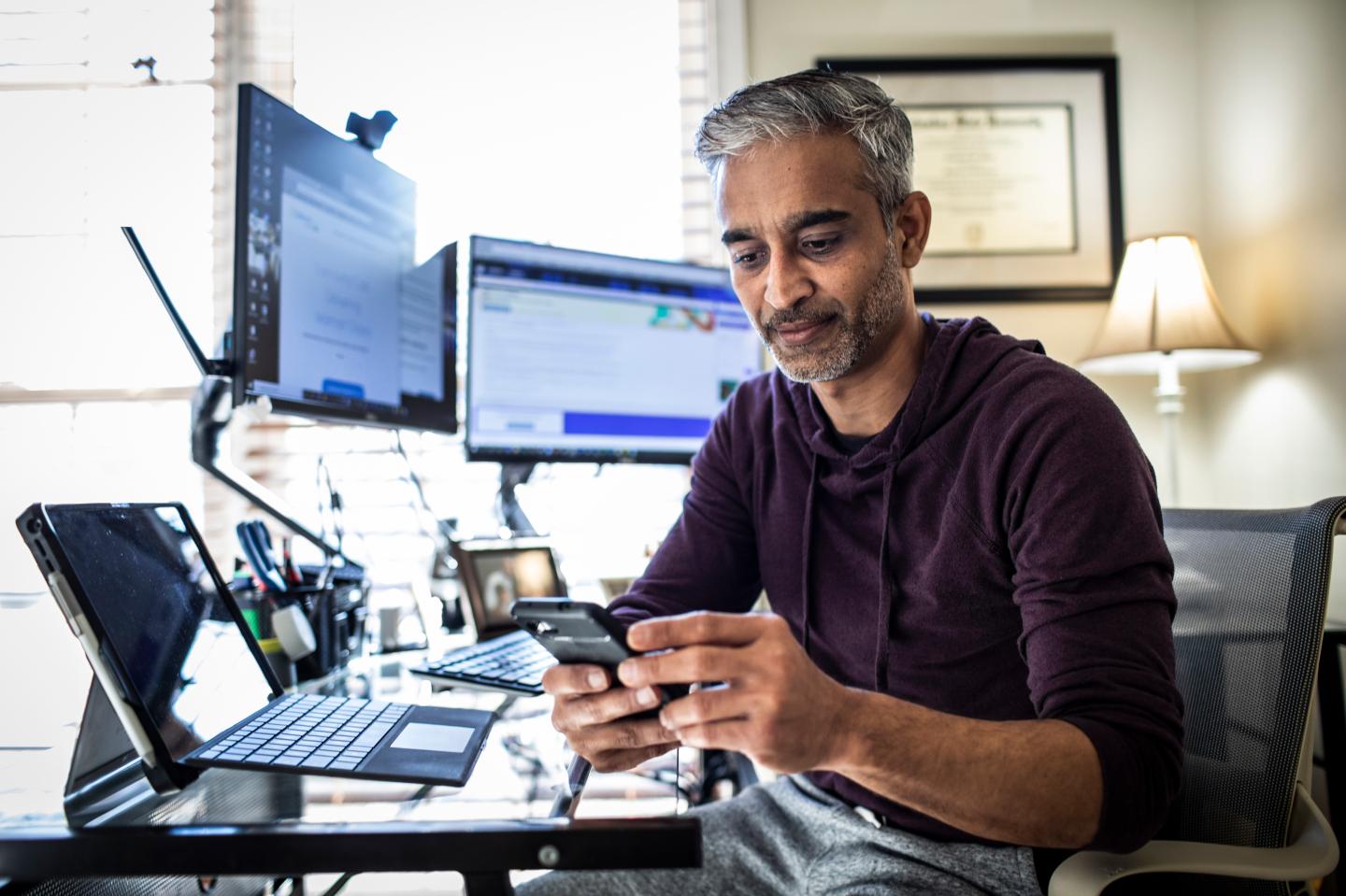 A man working from a home office using multiple monitors