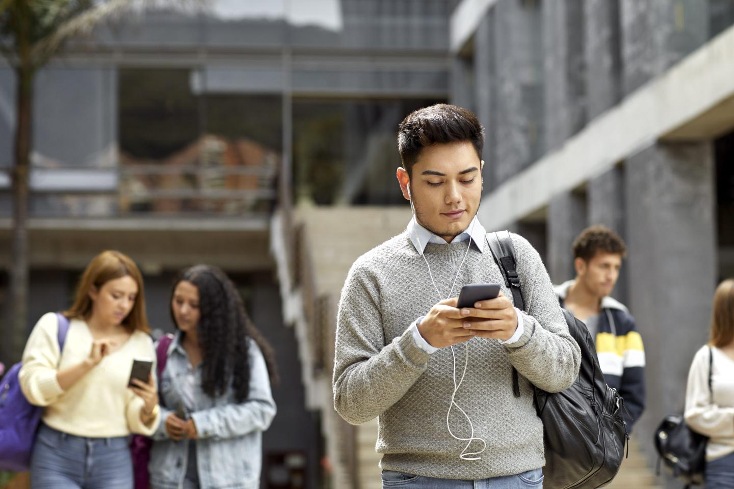 Student texting from cell in university campus