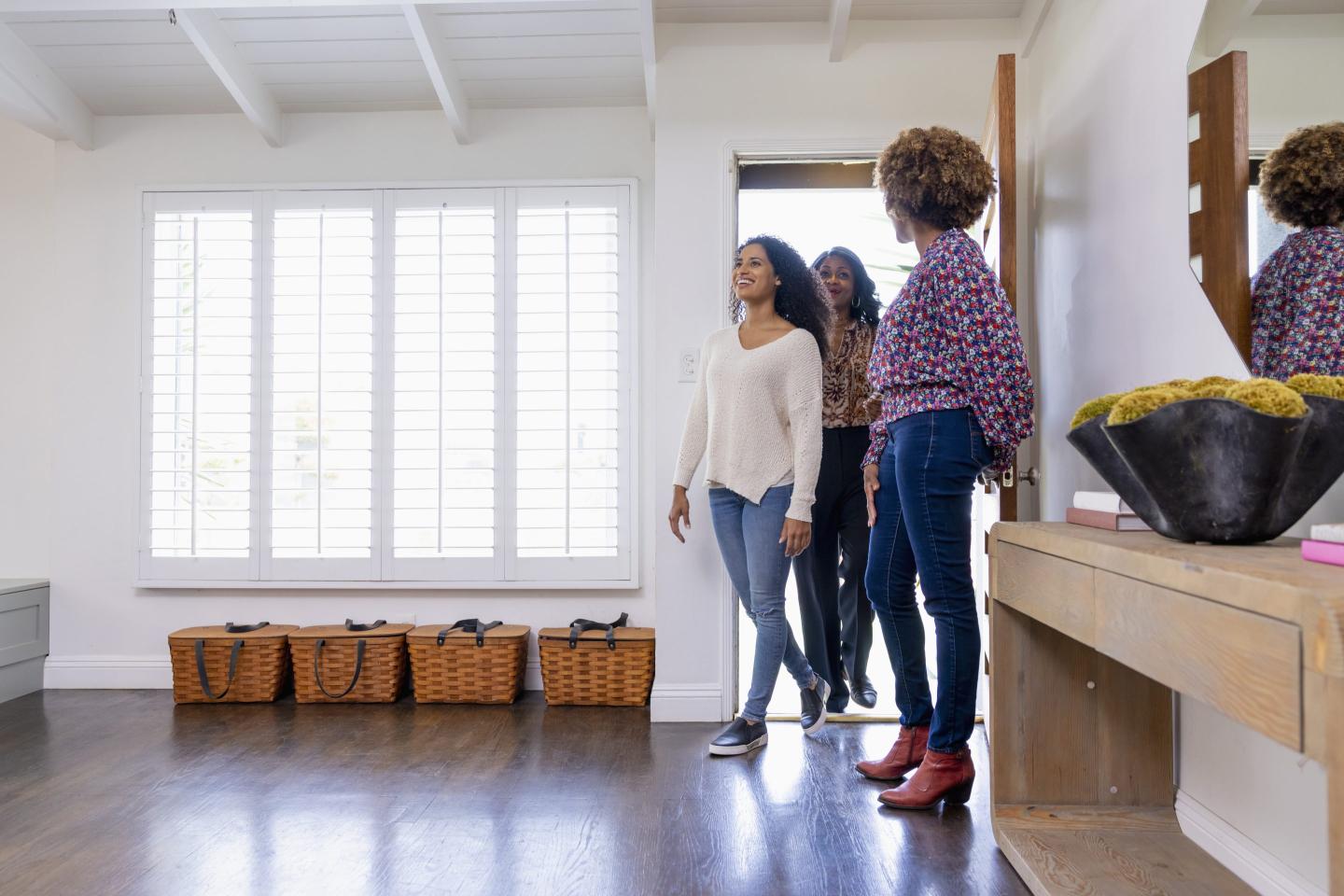 Smiling female customers entering through front door with real estate agent