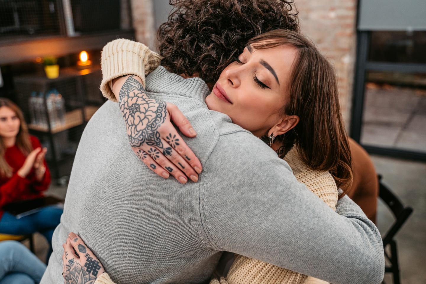 A woman embracing someone with an understanding look on her face.