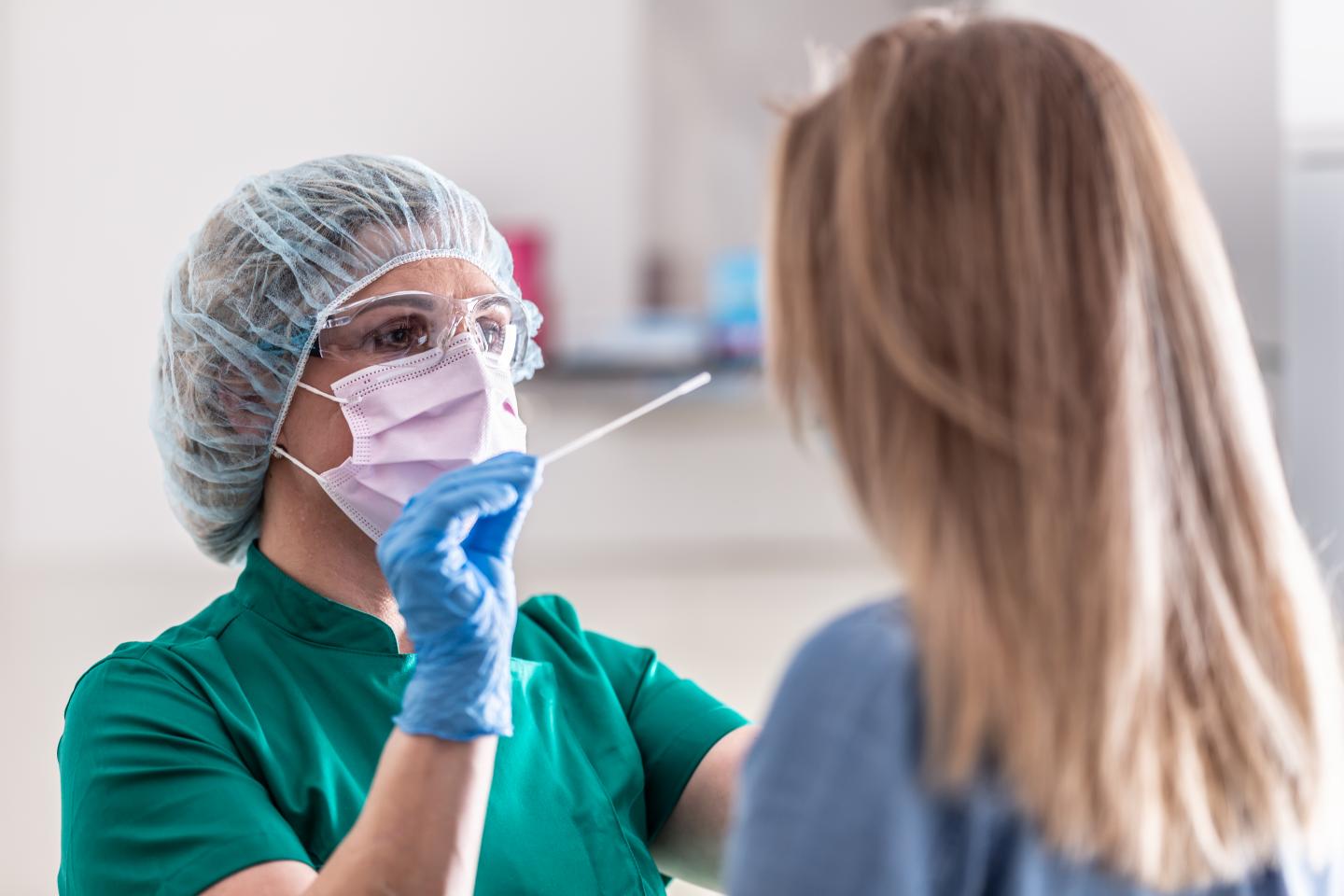 Well-protected medical staff performs swab test for COVID-19.