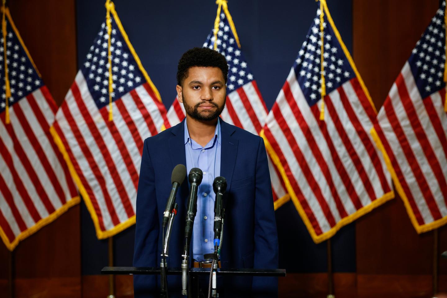 Rep. Maxwell Frost standing in front of American flags.
