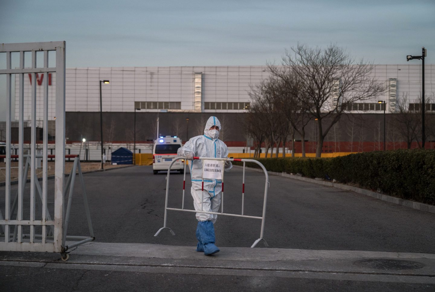 A Chinese health care worker in PPE sets up a barricade in Beijing